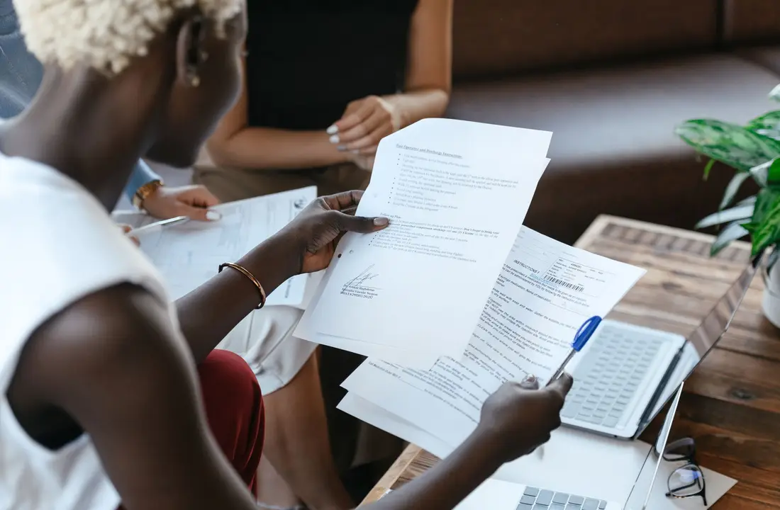 From above of crop anonymous African American female comparing data in papers at table of office