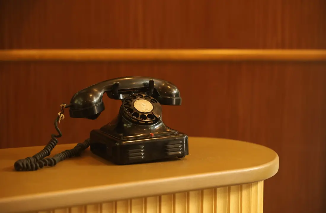 Classic black rotary phone on a stylish hotel front desk, emphasizing retro communication style.