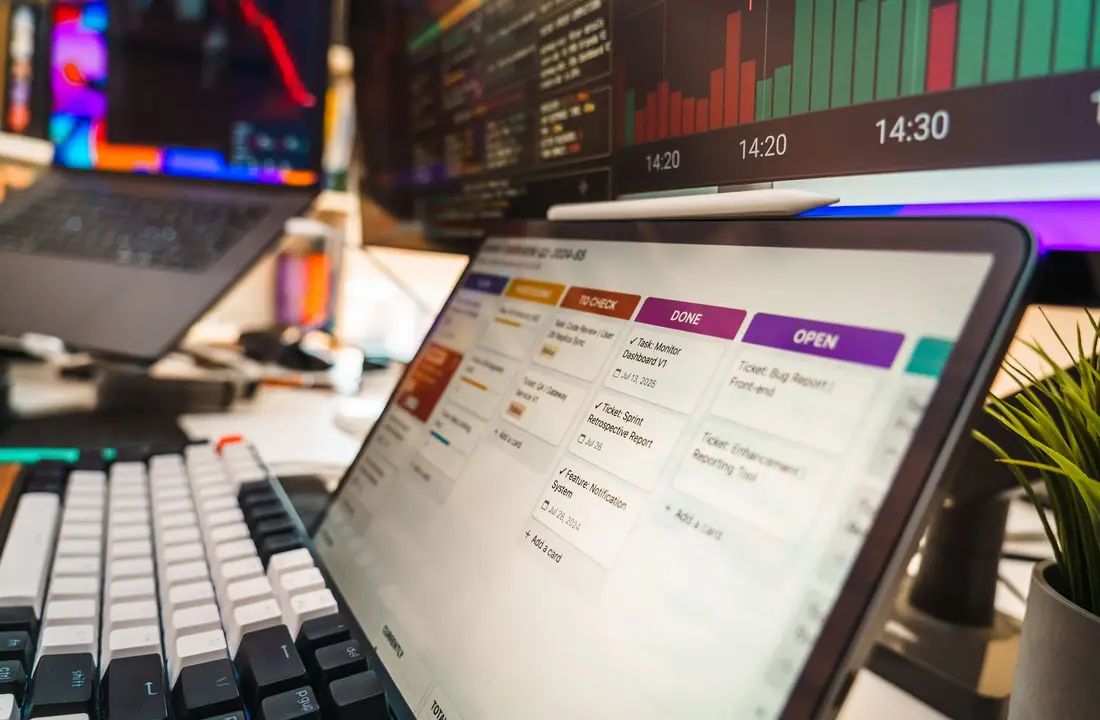A dynamic office setup featuring multi-screen displays with data charts and project management tools, perfect for tech or business environments.