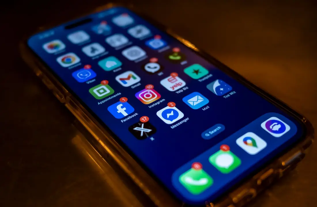 Smartphone screen displaying social media app notifications in a dimly lit setting.
