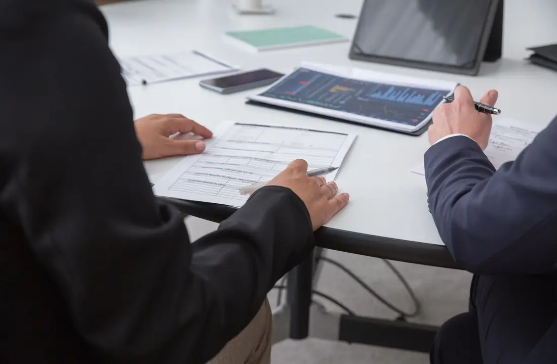 Close-up of professionals reviewing documents in an office setting, focused on analytics.