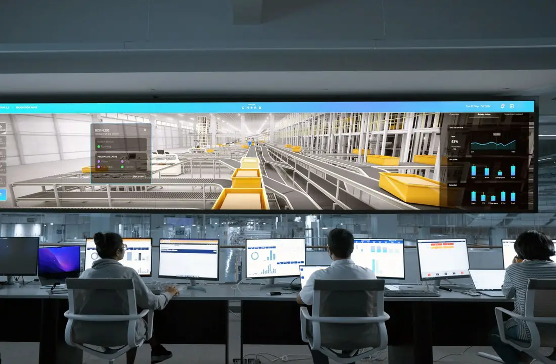 Modern control room with people monitoring large digital displays and computer systems.