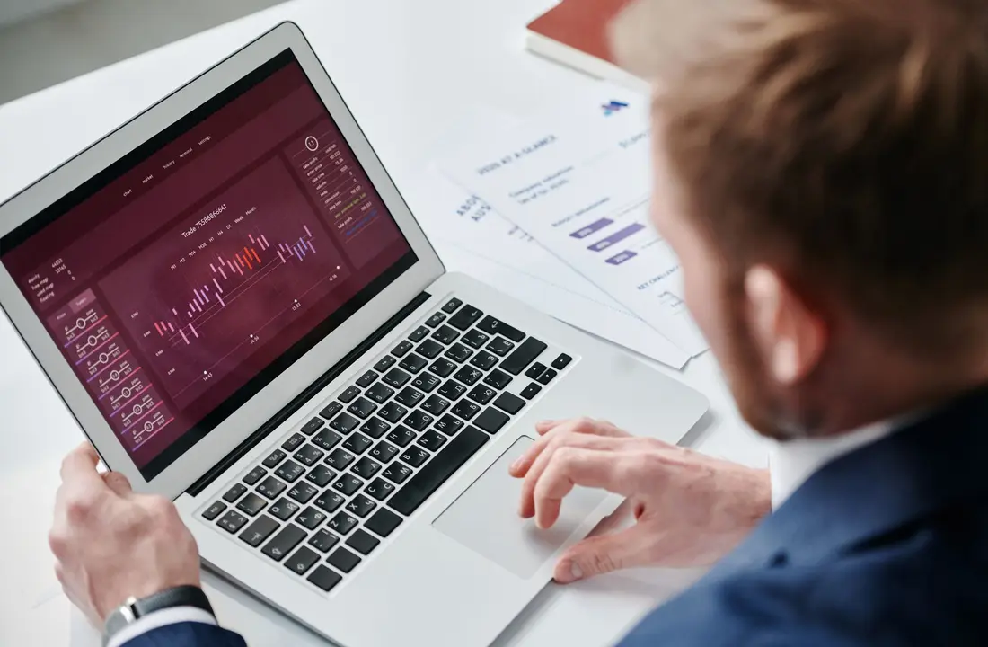 Businessman reviewing data analytics dashboard on laptop in bright office.
