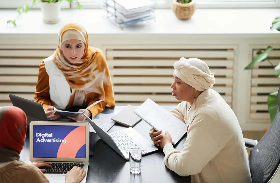 Trois personnes travaillant ensemble sur des visuels publicitaires autour d'une table